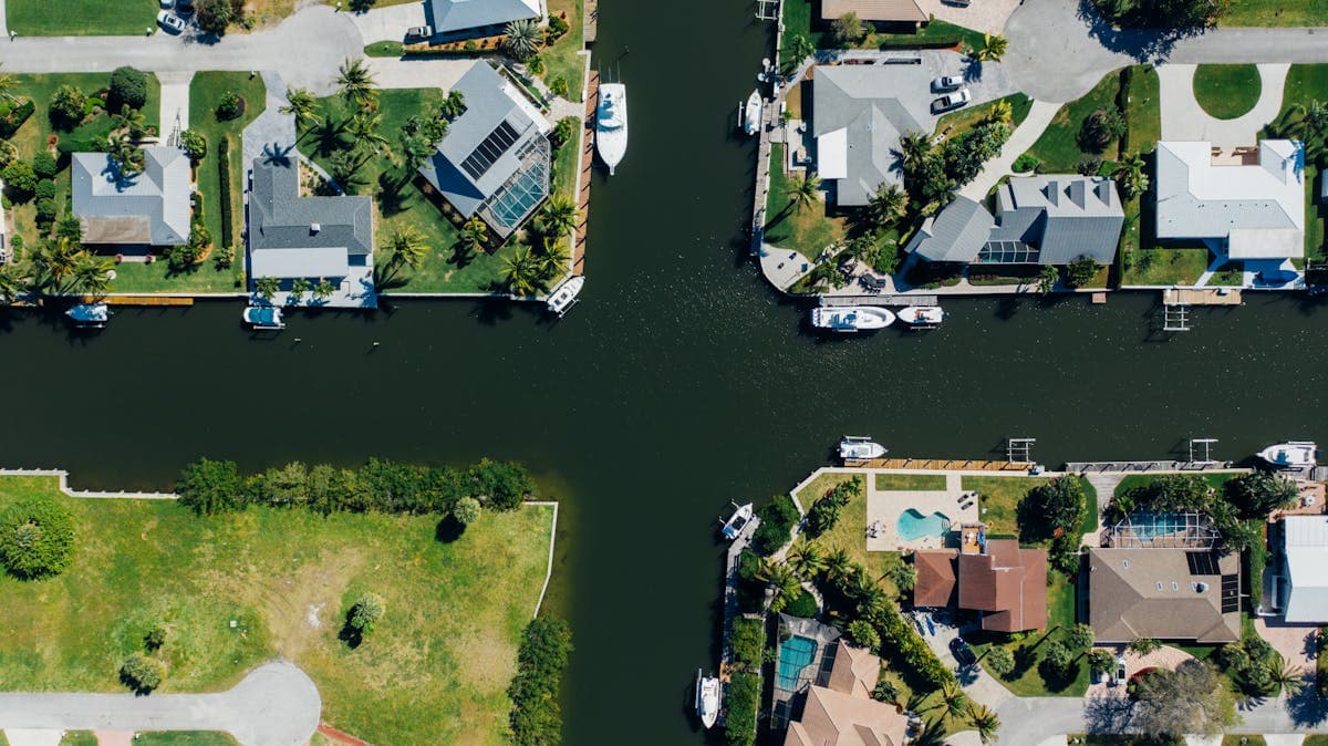 Aerial view of a sunny waterfront neighborhood with homes and boats